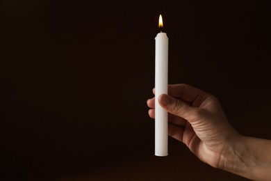 Photo of Woman holding burning church candle on black background, closeup. Space for text