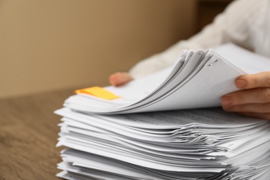 Photo of Woman stacking documents at wooden table indoors, closeup