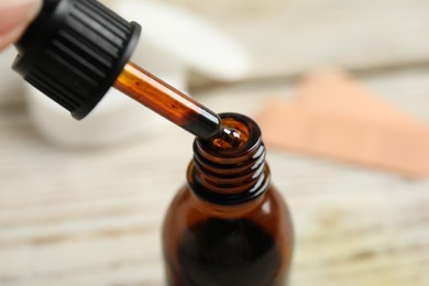 Photo of Dripping medical iodine from pipette into glass bottle, closeup