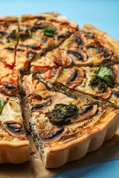 Photo of Delicious quiche with mushrooms on light blue table, closeup