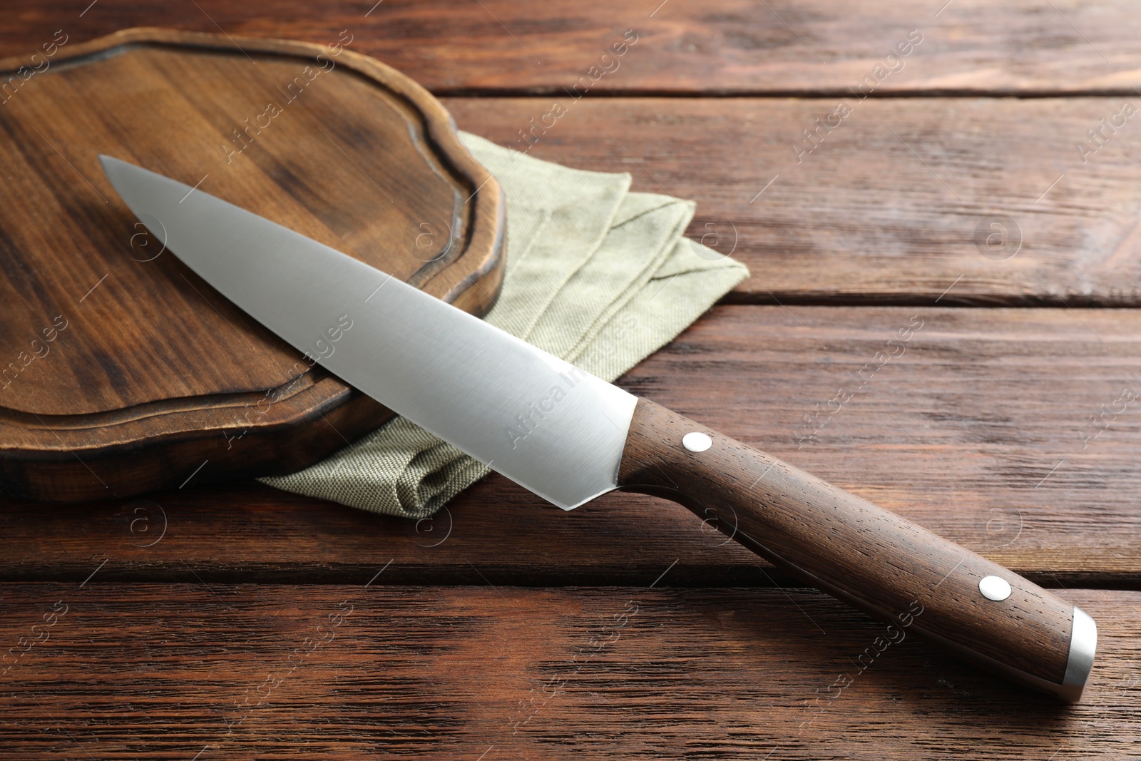 Photo of One sharp knife and board on wooden table, closeup