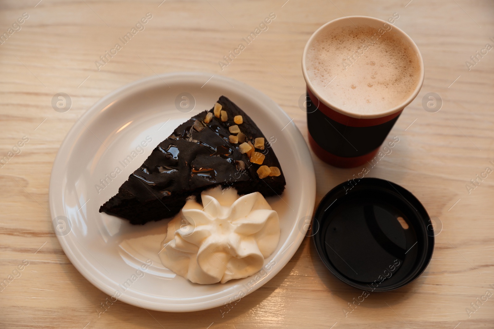 Photo of Tasty coffee in takeaway paper cup and dessert on white wooden table, above view