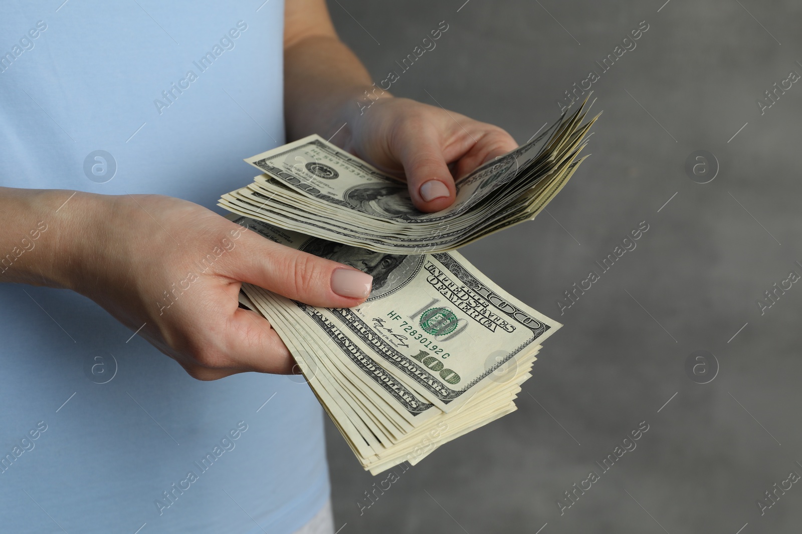 Photo of Money exchange. Woman counting dollar banknotes on grey background, closeup