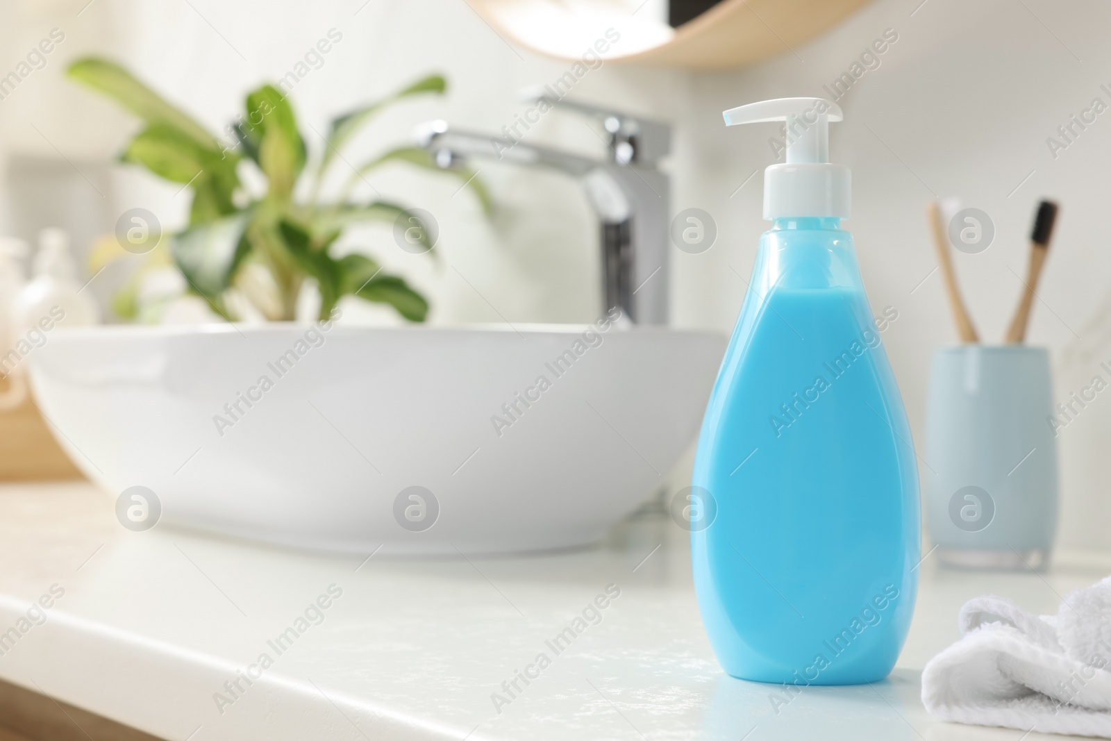 Photo of Dispenser of liquid soap on white table in bathroom, space for text