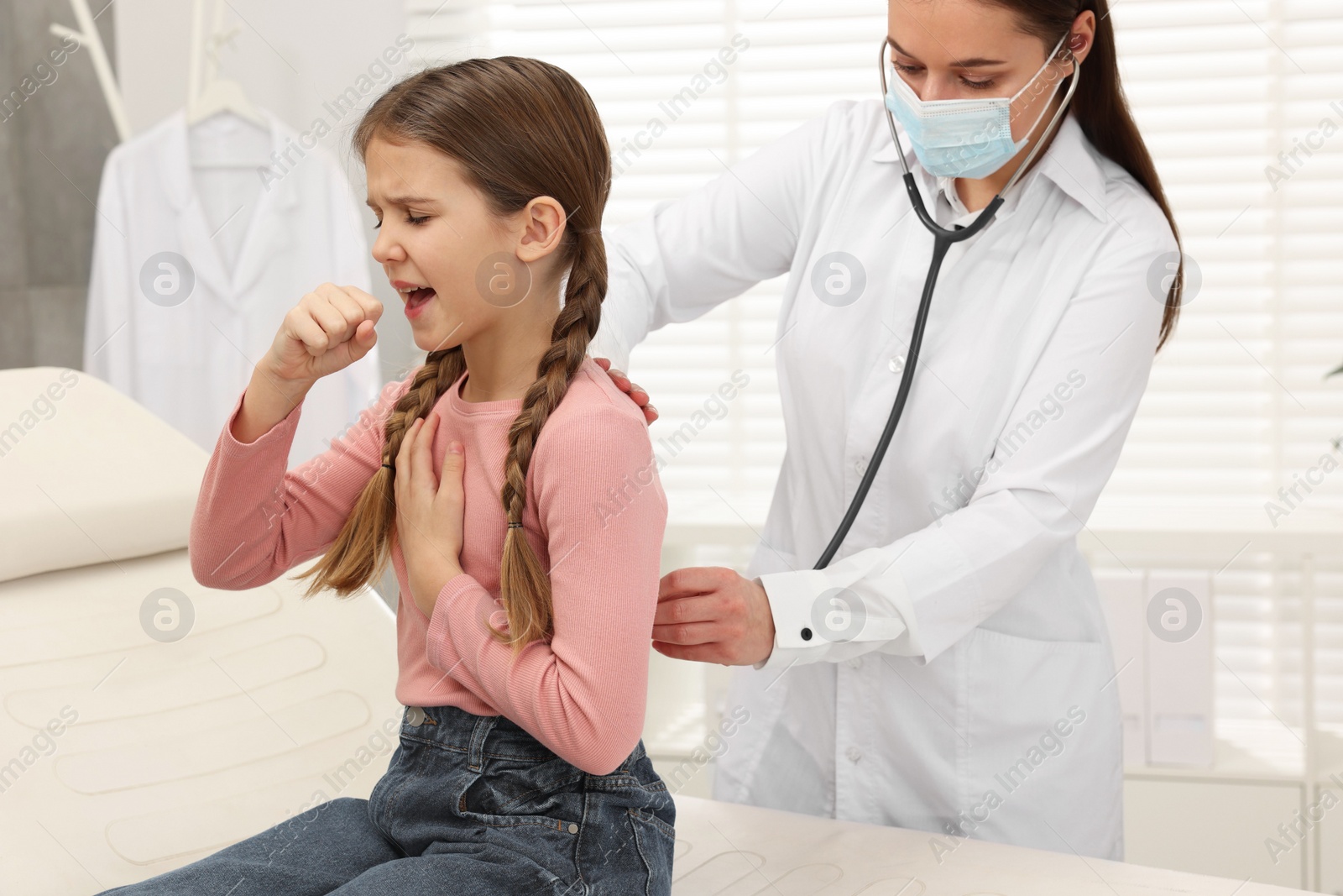 Photo of Doctor examining coughing girl in hospital. Cold symptoms