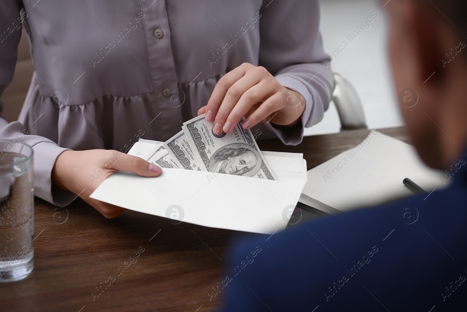 Photo of Woman with bribe money at table, closeup