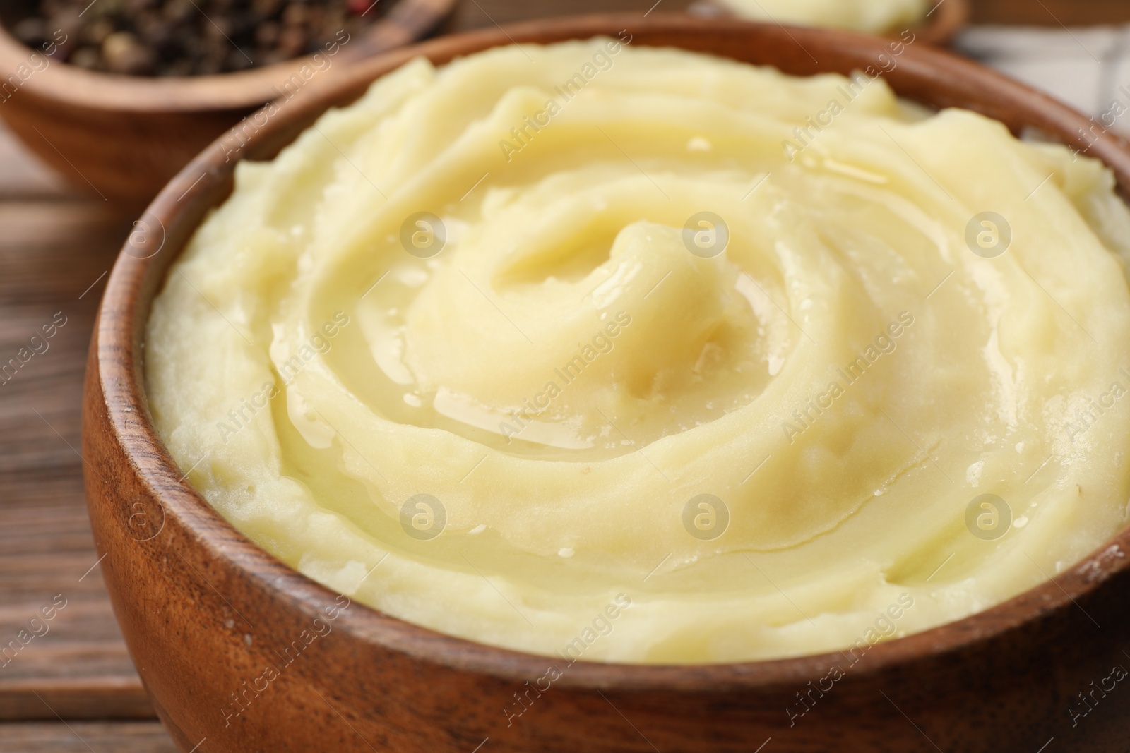 Photo of Bowl of tasty mashed potato and pepper on wooden table, closeup