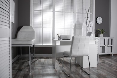 Modern medical office interior with doctor's workplace and examination table