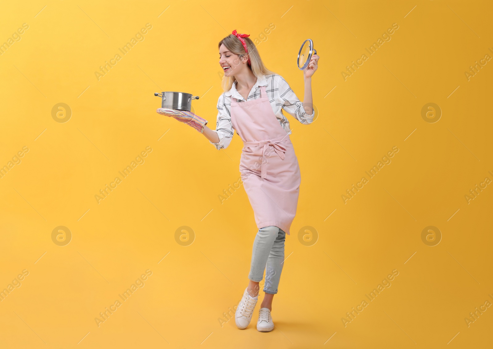 Photo of Young housewife with pot on yellow background