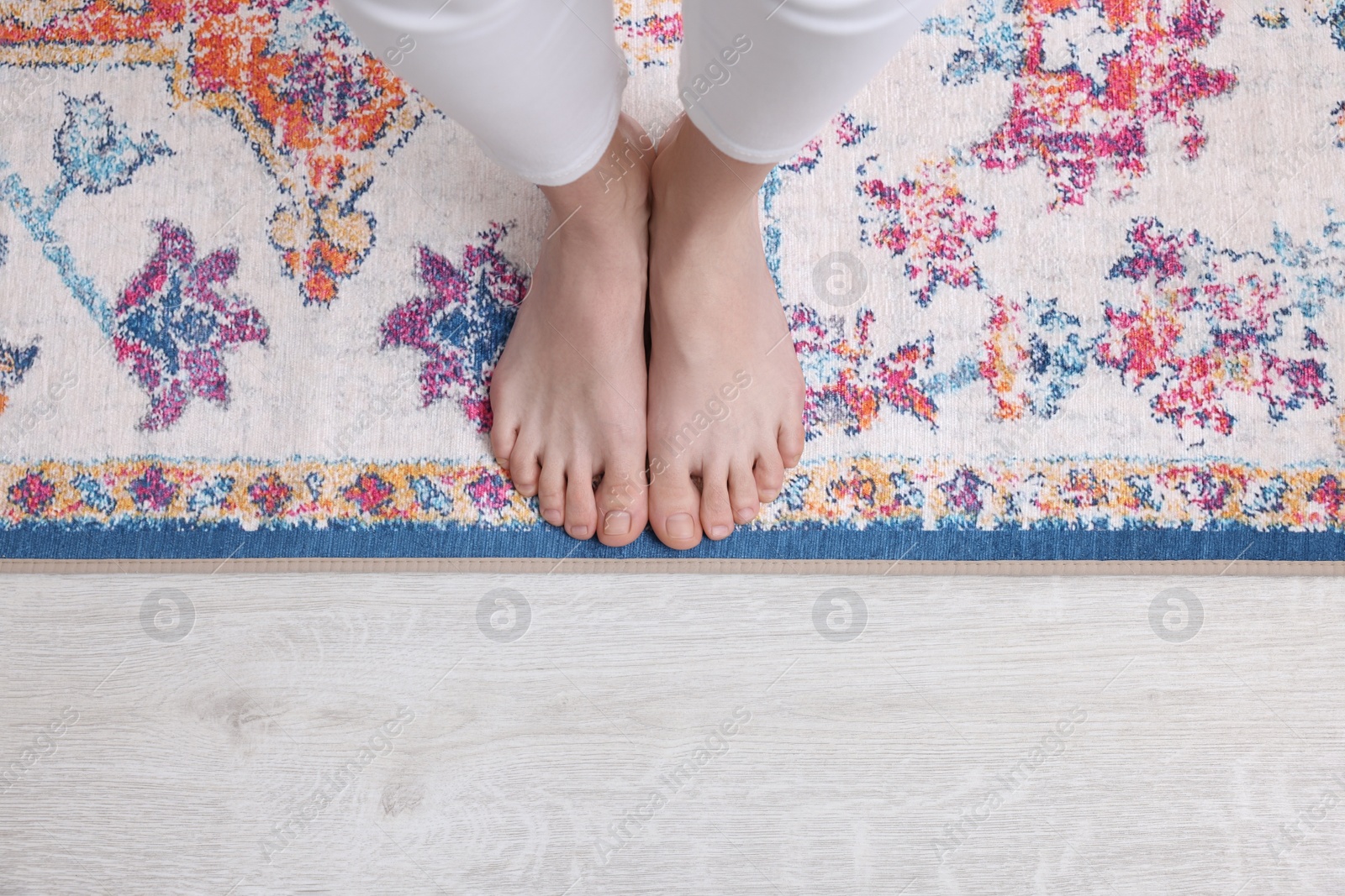 Photo of Woman standing on carpet with pattern at home, top view