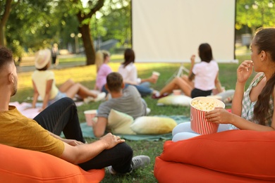 Photo of Young people with popcorn watching movie in open air cinema. Space for text