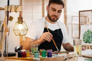 Young man painting with brush in artist studio