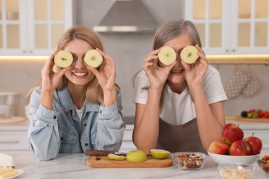 Happy mature mother and her daughter having fun in kitchen