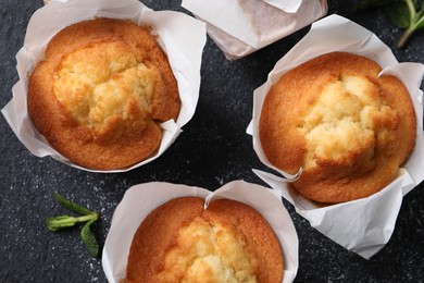 Photo of Delicious sweet muffins on black textured table, flat lay