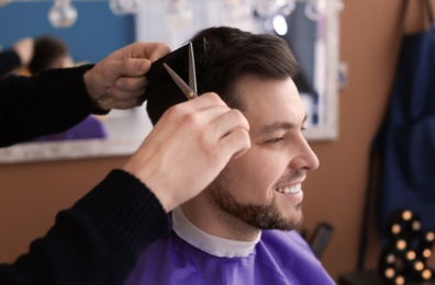 Professional hairdresser working with client in beauty salon, closeup