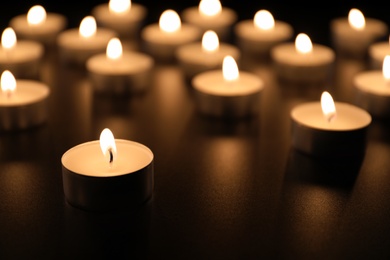 Photo of Burning candles on table in darkness, space for text. Funeral symbol