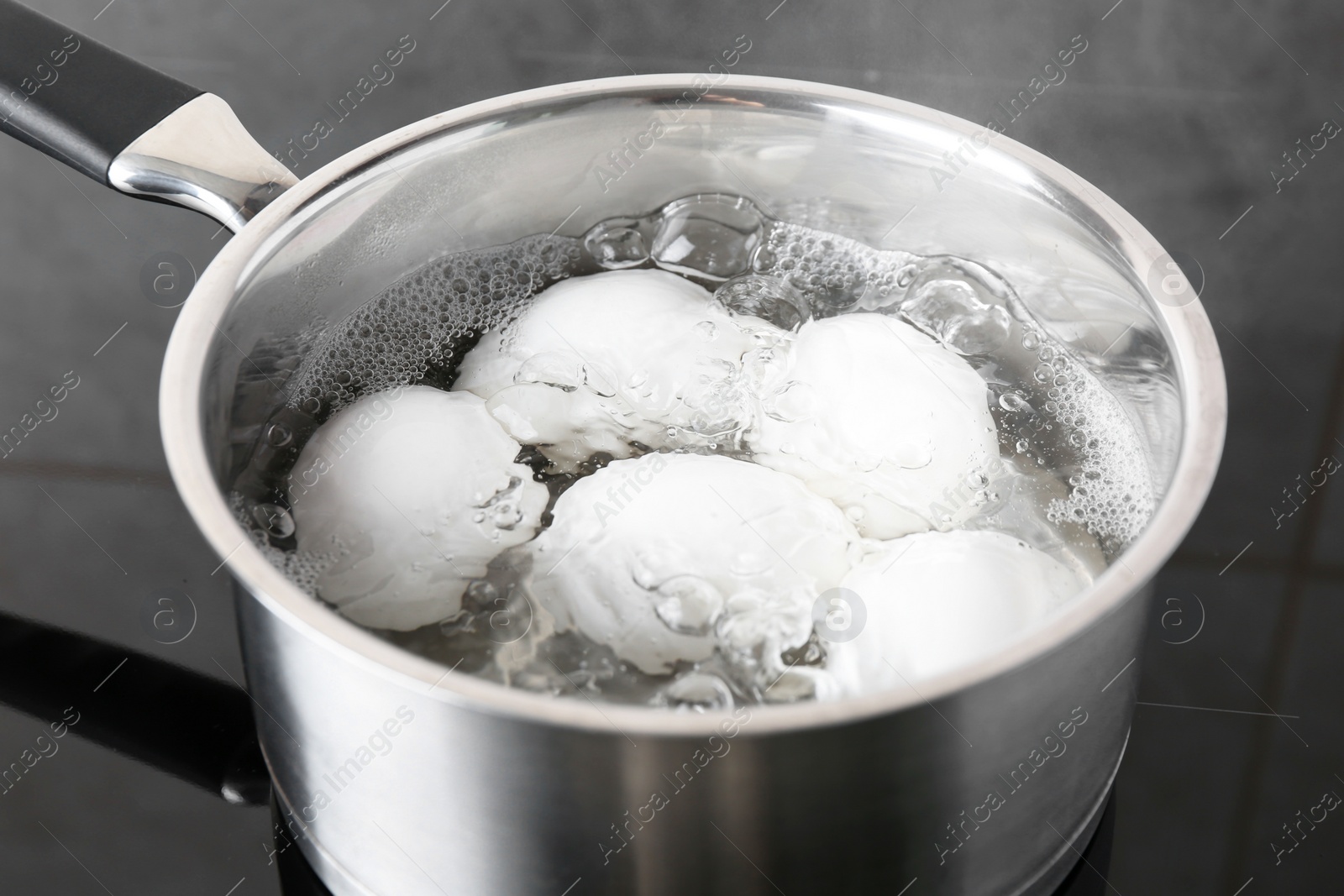 Photo of Chicken eggs boiling in saucepan on electric stove, closeup