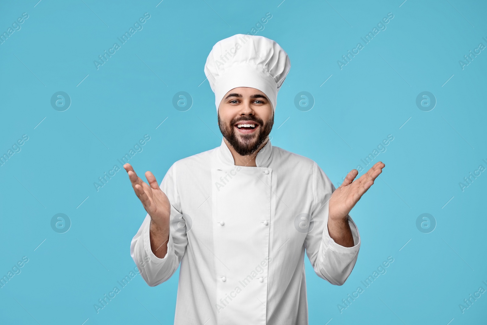 Photo of Happy young chef in uniform on light blue background