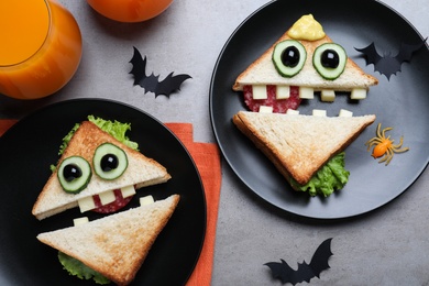 Photo of Cute monster sandwiches served on grey table, flat lay . Halloween party food