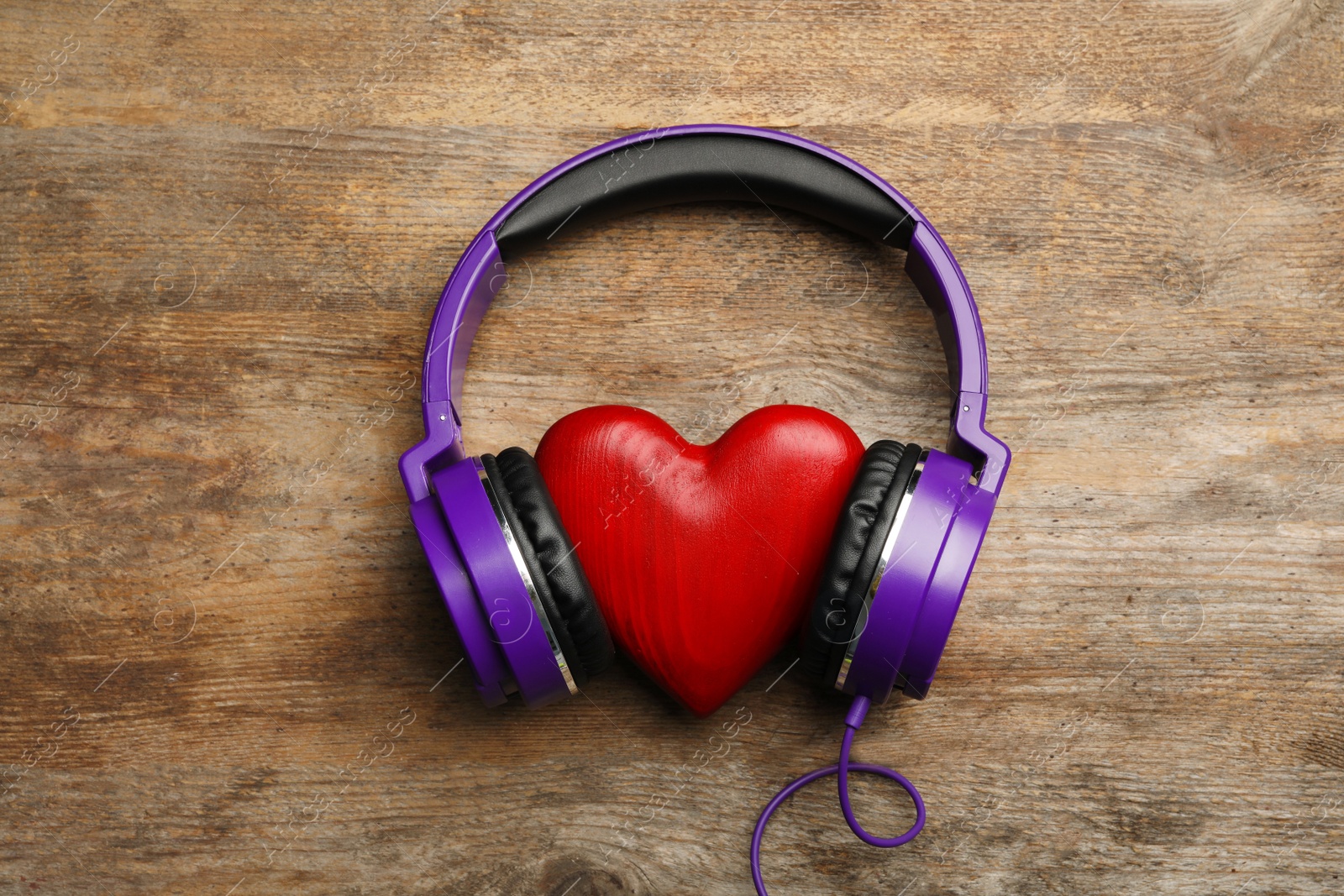 Photo of Decorative heart with modern headphones on wooden background, top view