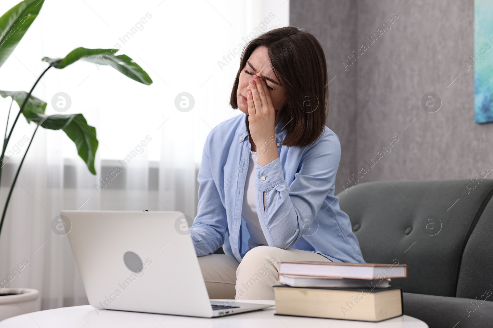 Photo of Overwhelmed woman sitting on sofa at home