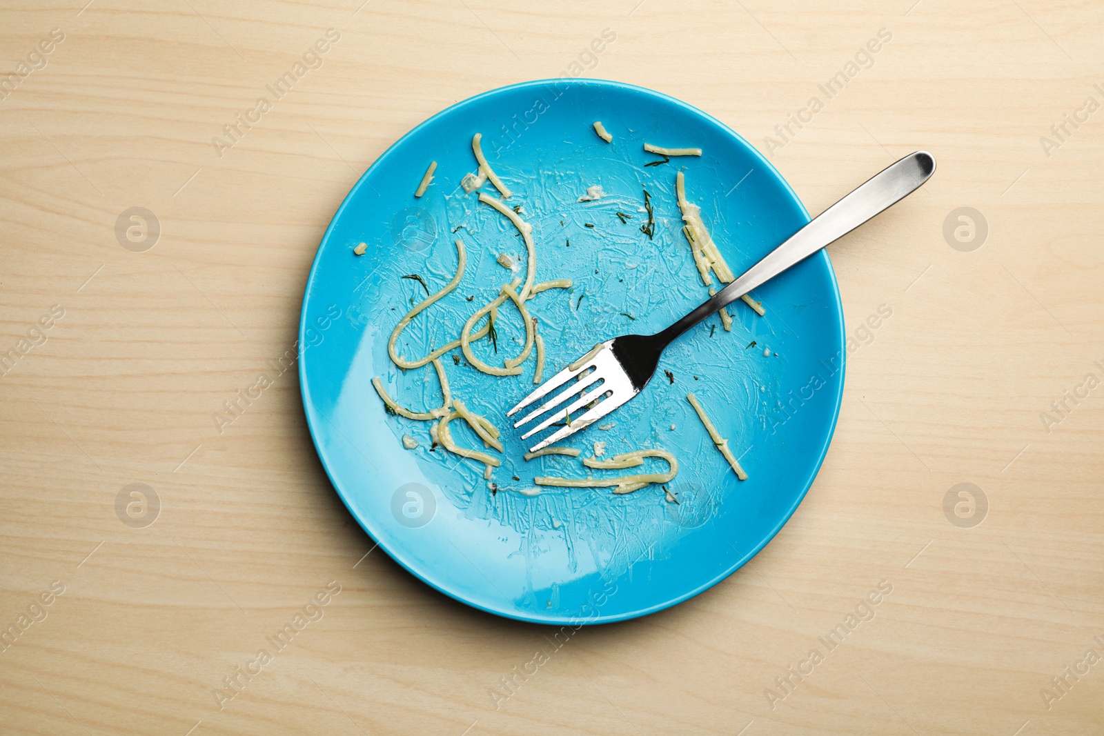 Photo of Dirty plate with food leftovers and fork on wooden background, top view