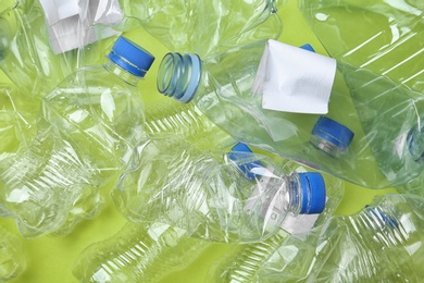 Pile of crumpled empty plastic bottles on color background, closeup. Recycling problem