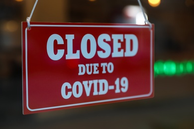 Photo of Red sign with words "Closed Due To Covid-19" hanging on glass door