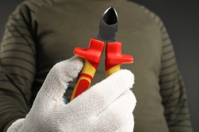 Photo of Man with diagonal pliers on dark background, closeup