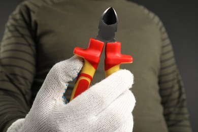 Man with diagonal pliers on dark background, closeup