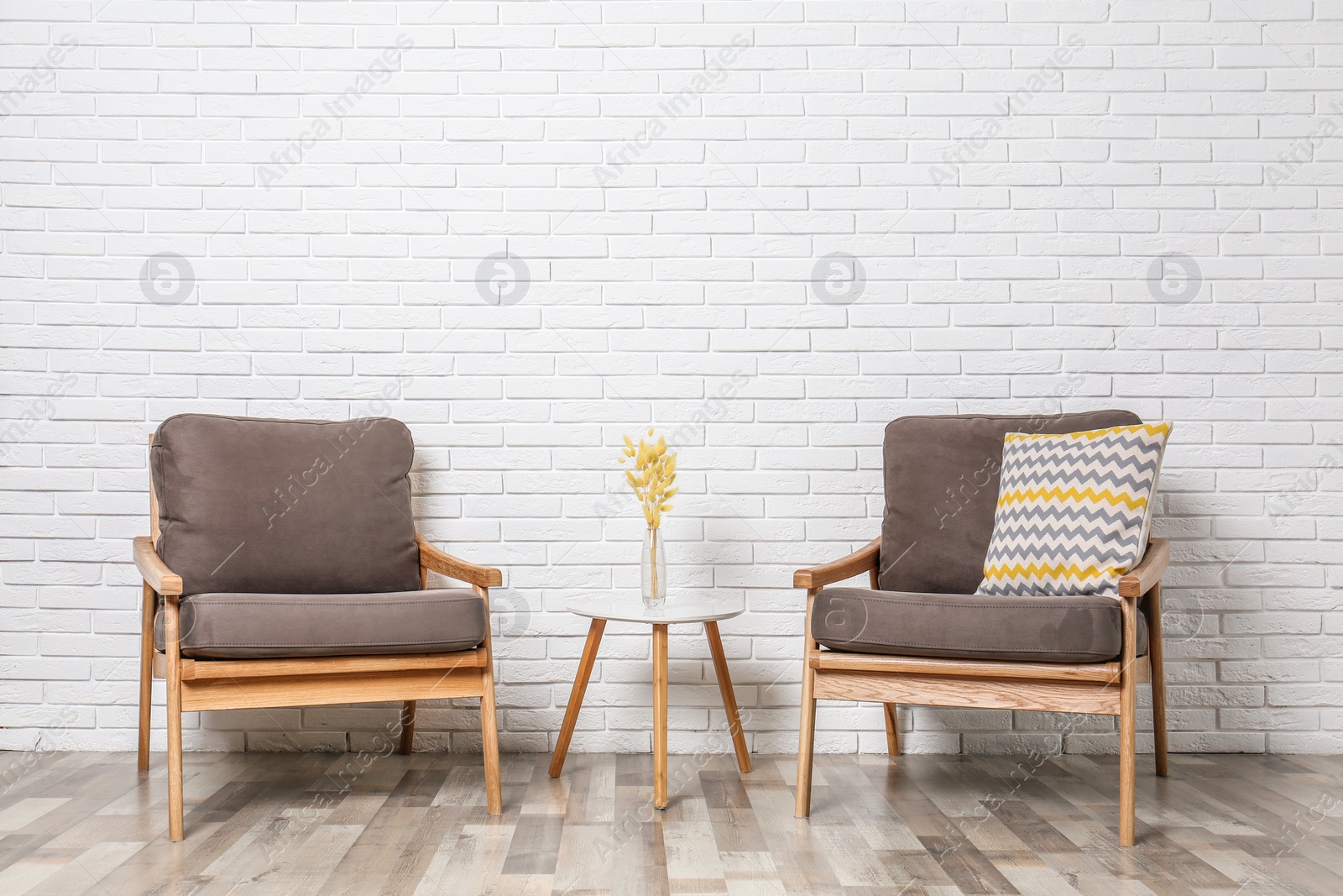 Photo of Room interior with modern armchairs and table near white brick wall