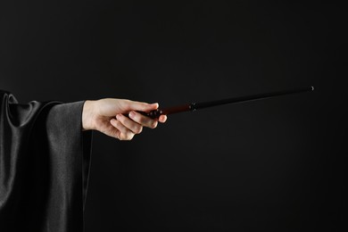Photo of Wizard holding magic wand on black background, closeup