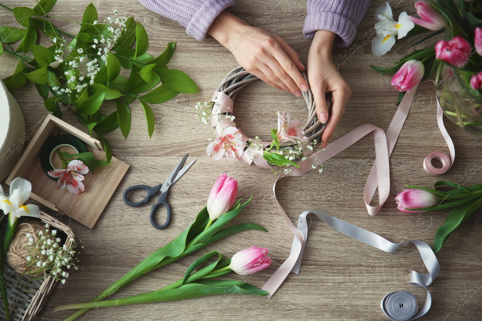 Photo of Female decorator creating beautiful bouquet at table, top view