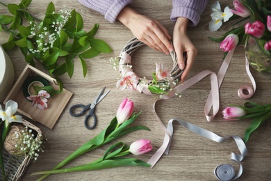 Photo of Female decorator creating beautiful bouquet at table, top view