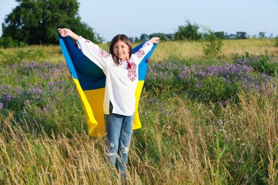Photo of Happy girl with national flag of Ukraine in field. Space for text