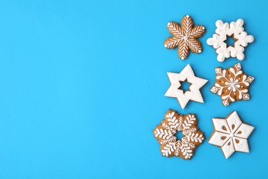 Photo of Christmas snowflake shaped gingerbread cookies on light blue background, flat lay. Space for text