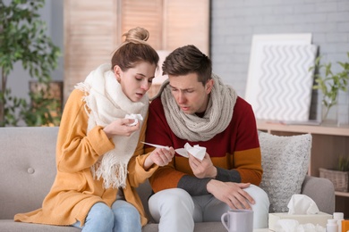 Photo of Couple suffering from cold together on sofa at home