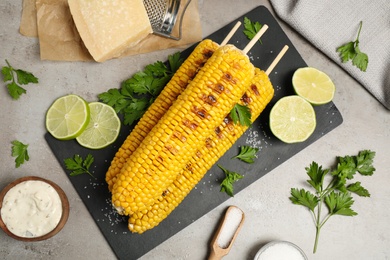 Photo of Delicious grilled corn cobs on grey table, flat lay