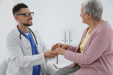 Photo of Doctor holding senior patient's hands in office