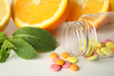 Photo of Bottle with vitamin pills and oranges on white table, closeup
