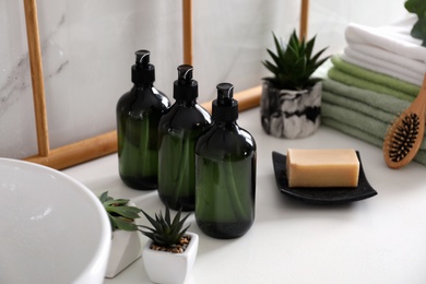 Photo of Soap dispensers and plants on countertop in bathroom