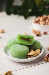 Photo of Delicious mochi and pistachios on white wooden table, closeup with space for text. Traditional Japanese dessert
