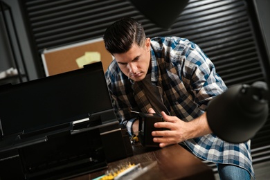 Photo of Professional repairman fixing modern printer in office