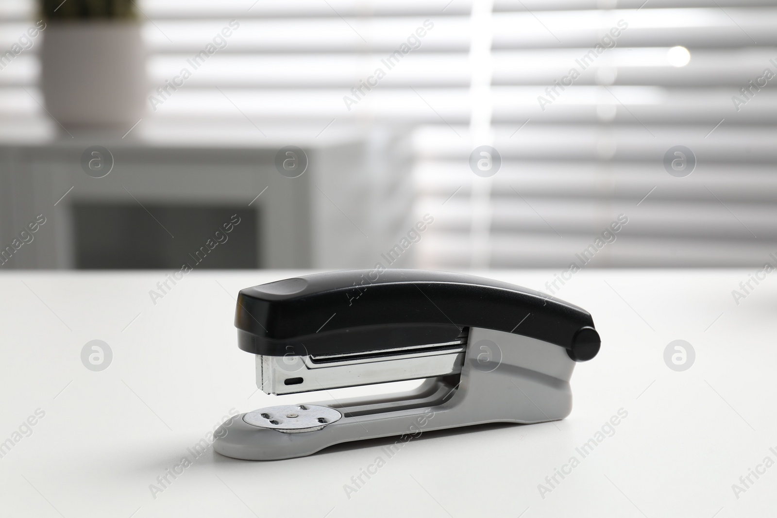 Photo of One stapler on white table indoors, closeup