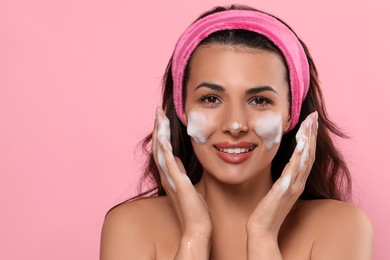 Photo of Beautiful woman applying facial cleansing foam on pink background, space for text