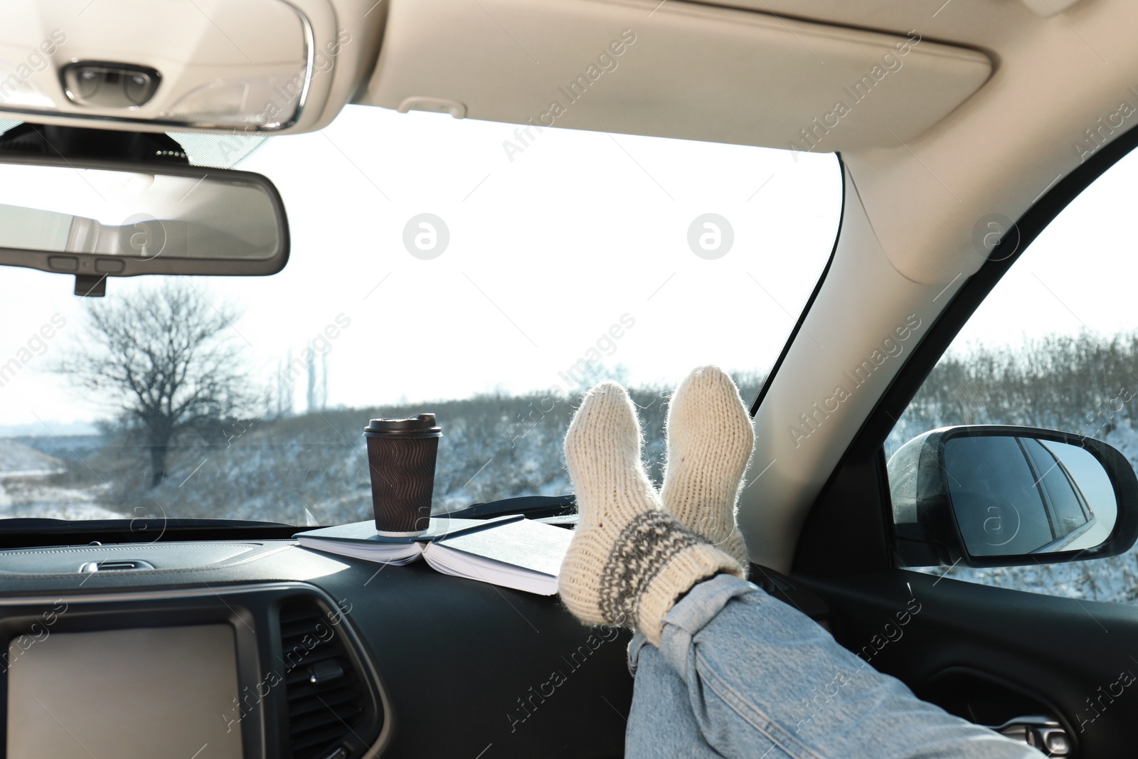 Young woman in warm socks holding her legs on car dashboard. Cozy atmosphere Photo of Young woman in warm socks holding her legs on car dashboard. Cozy atmosphere