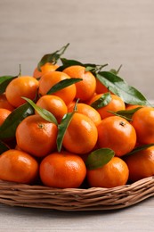 Photo of Fresh ripe juicy tangerines and green leaves on white wooden table