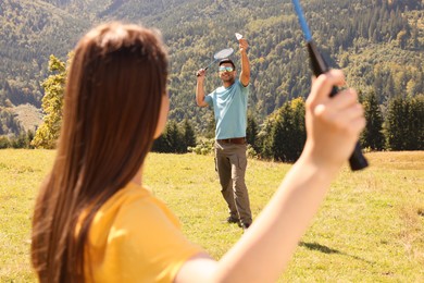 Photo of Couple playing badminton in mountains on sunny day