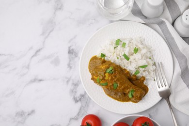 Photo of Delicious rice and chicken with curry sauce served on white marble table, flat lay. Space for text