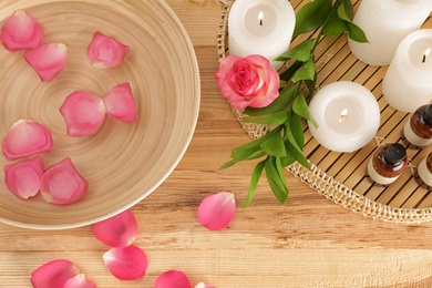 Photo of Flat lay composition with bowl of water, rose petals and candles on table. Spa treatment